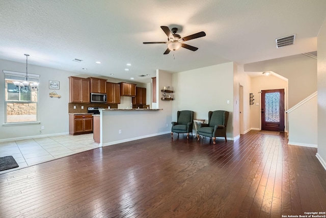 living area featuring a chandelier, ceiling fan, light wood-style floors, plenty of natural light, and recessed lighting