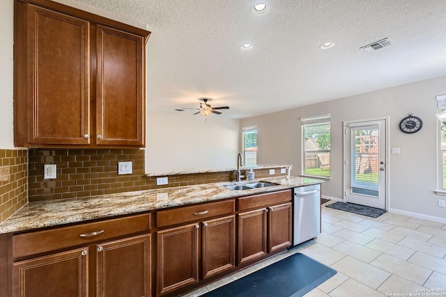 kitchen featuring stainless steel dishwasher, a sink, a peninsula, decorative backsplash, and a textured ceiling