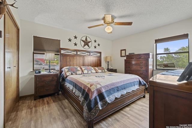 2050 Adj Ln, Fredericksburg, TX 78624 - bedroom featuring multiple windows, wood finished floors, a textured ceiling, and a ceiling fan