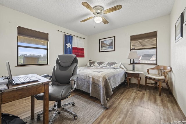 2050 Adj Ln, Fredericksburg, TX 78624 - bedroom with wood finished floors, a desk, a textured ceiling, and a ceiling fan