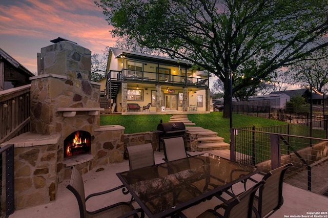 315 E Klein, New Braunfels, TX 78130 - back of house at dusk featuring stairs, an outdoor stone fireplace, a patio area, and outdoor dining area
