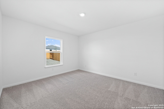carpeted empty room featuring baseboards