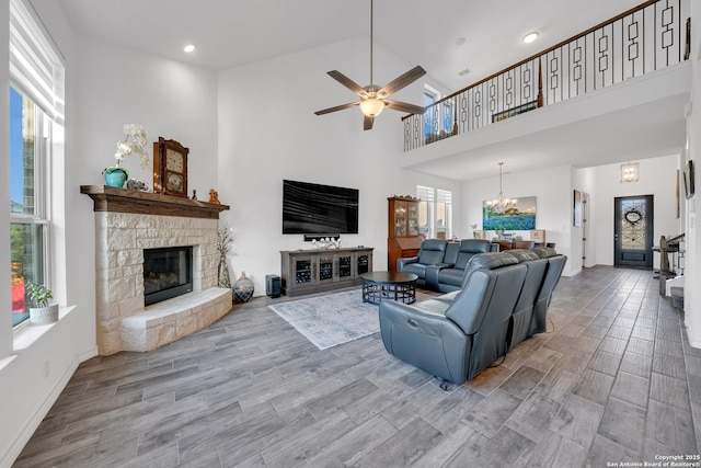 11109 Molly Run, San Antonio, TX 78254 - living area featuring a high ceiling, a stone fireplace, ceiling fan, baseboards, and wood finished floors