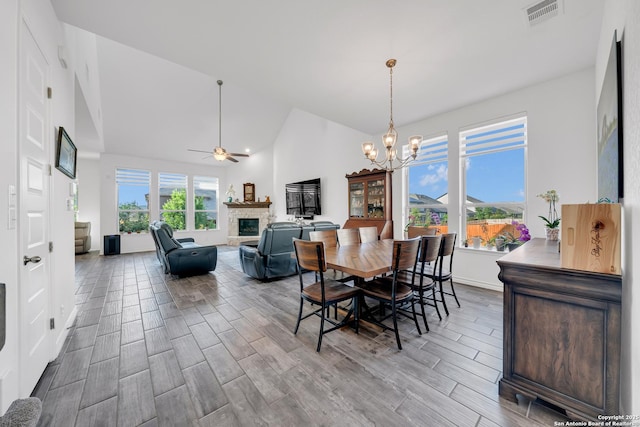 11109 Molly Run, San Antonio, TX 78254 - dining space featuring a stone fireplace, wood finished floors, a chandelier, ceiling fan, and high vaulted ceiling