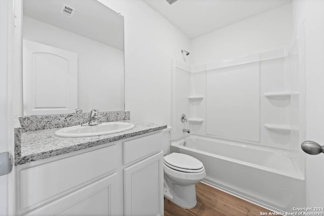 bathroom featuring wood finished floors, toilet, vanity, and bathing tub / shower combination