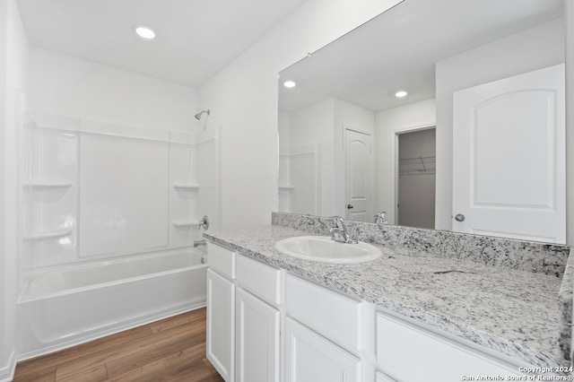 full bathroom with wood finished floors, vanity, bathtub / shower combination, recessed lighting, and a walk in closet