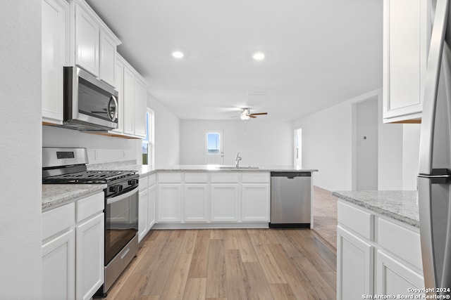 kitchen with appliances with stainless steel finishes, a sink, a peninsula, a ceiling fan, and white cabinets