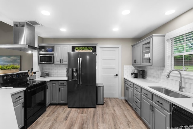 296 Cherokee Dr, Bandera, TX 78003 - kitchen with black appliances, gray cabinets, a sink, island range hood, and light wood-style floors