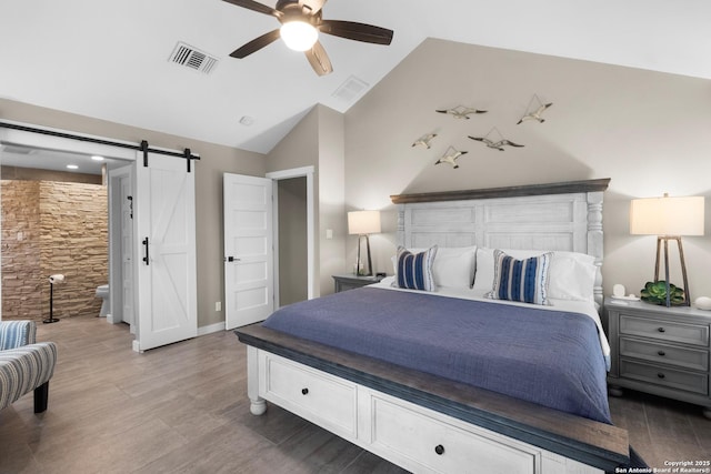 296 Cherokee Dr, Bandera, TX 78003 - bedroom featuring vaulted ceiling, wood finished floors, a barn door, and ceiling fan