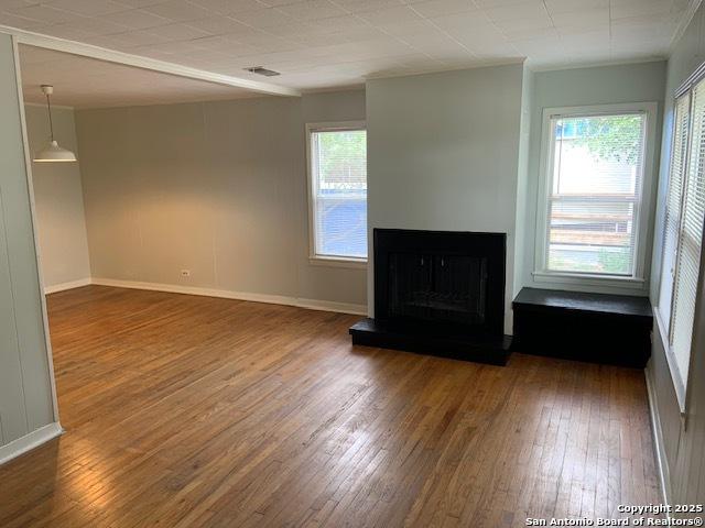 434 Hermine, San Antonio, TX 78212 - unfurnished living room featuring hardwood / wood-style flooring, a fireplace with raised hearth, and baseboards