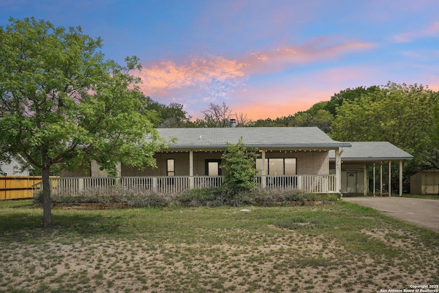 140 Should Bee, Ingram, TX 78025 - ranch-style home featuring a porch, a carport, driveway, a storage unit, and brick siding
