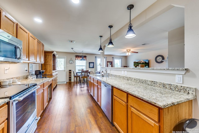 kitchen with stainless steel appliances, a sink, a ceiling fan, dark wood-style flooring, and light stone countertops