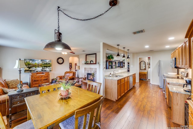 dining space with a fireplace, dark wood-style floors, and recessed lighting