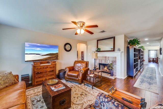 living room featuring wood finished floors, a fireplace, and ceiling fan