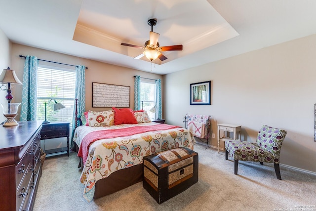 bedroom with light colored carpet, a raised ceiling, crown molding, ceiling fan, and baseboards