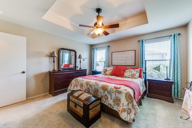 carpeted bedroom with a tray ceiling and ceiling fan
