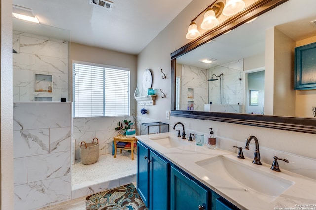 bathroom with a marble finish shower and double vanity