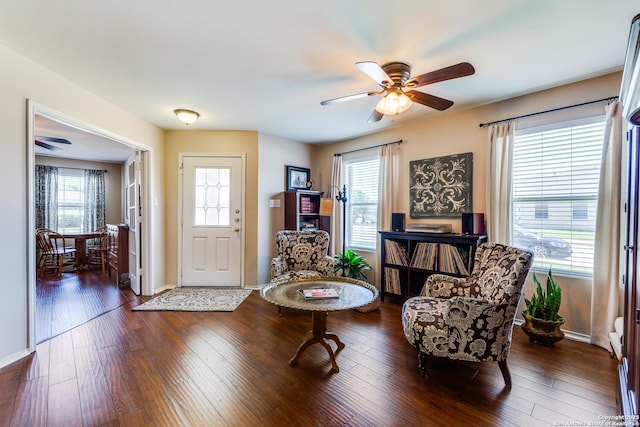living room featuring a ceiling fan, healthy amount of natural light, dark wood-type flooring, and baseboards
