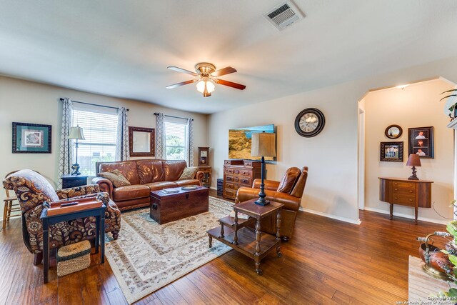living area with a ceiling fan, wood-type flooring, arched walkways, and baseboards