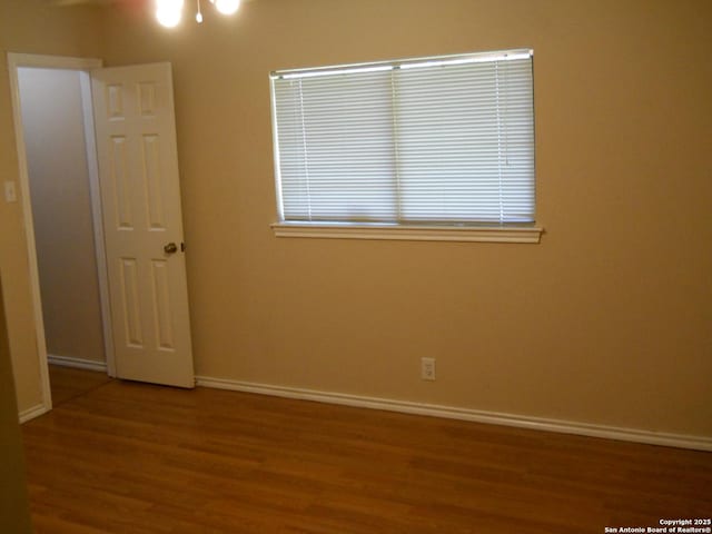 empty room featuring wood finished floors and baseboards