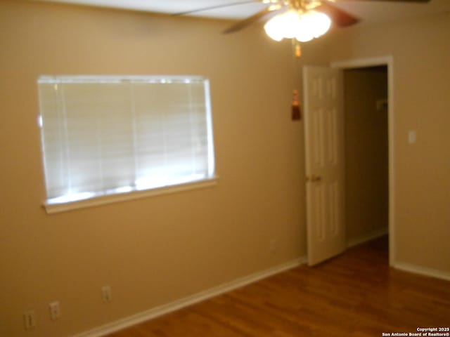 unfurnished room with ceiling fan, wood finished floors, and baseboards