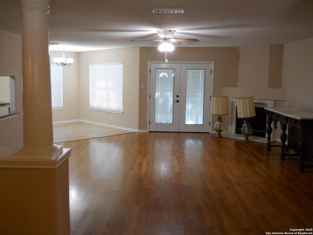 foyer entrance with ornate columns, wood finished floors, ceiling fan, and a chandelier