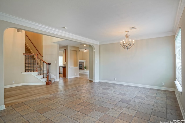 unfurnished room featuring a chandelier, stone tile floors, baseboards, ornamental molding, and stairway