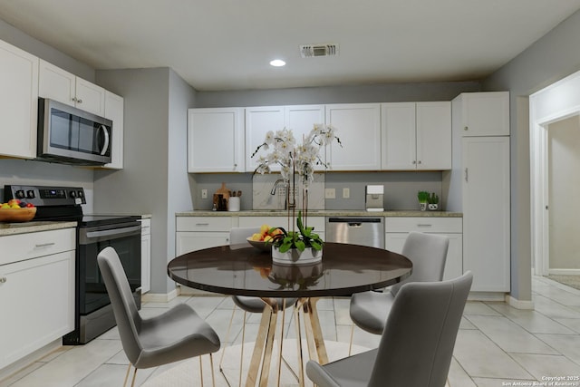 4342 Lehman Dr, Kirby, TX 78219 - kitchen with appliances with stainless steel finishes, white cabinets, recessed lighting, light countertops, and light tile patterned flooring