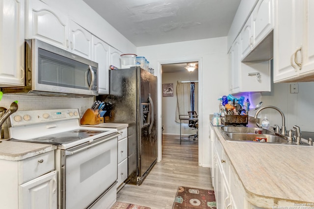 5118 Crusade Dr, San Antonio, TX 78218 - kitchen with white electric range, stainless steel microwave, a sink, light wood finished floors, and white cabinets