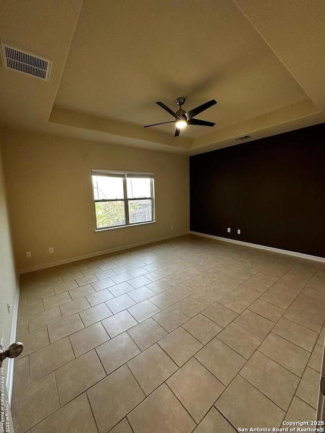 6635 Cibola Frst, San Antonio, TX 78233 - spare room featuring a tray ceiling, light tile patterned flooring, a ceiling fan, and baseboards