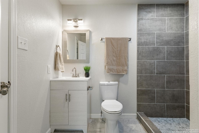 3115 Bluefield, San Antonio, TX 78230 - bathroom featuring toilet, vanity, tiled shower, marble look tile flooring, and baseboards