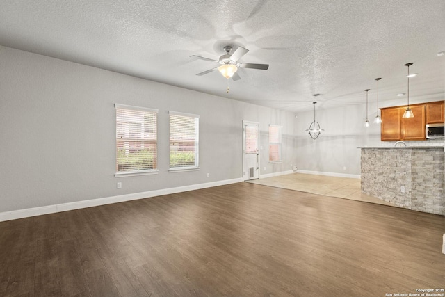 10307 Royal, San Antonio, TX 78245 - unfurnished living room featuring a ceiling fan, light wood-type flooring, a textured ceiling, and baseboards