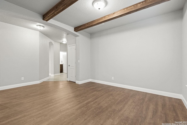 10307 Royal, San Antonio, TX 78245 - empty room with beamed ceiling, arched walkways, dark wood-style floors, baseboards, and a textured ceiling