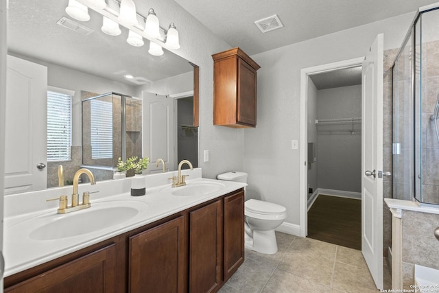 10307 Royal, San Antonio, TX 78245 - bathroom with a walk in closet, a stall shower, double vanity, tile patterned flooring, and a textured ceiling