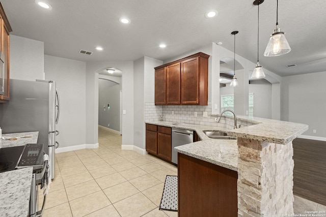 10307 Royal, San Antonio, TX 78245 - kitchen featuring stainless steel appliances, arched walkways, baseboards, a peninsula, and a sink