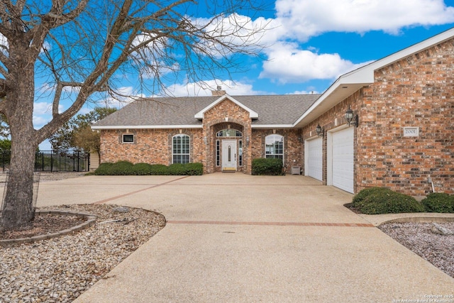 2001 Crown Rdg, Kerrville, TX 78028 - view of front facade with driveway, a garage, brick siding, a chimney, and roof with shingles