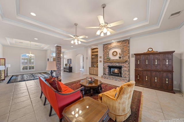 2001 Crown Rdg, Kerrville, TX 78028 - living room with a raised ceiling, light tile patterned flooring, a brick fireplace, crown molding, and ceiling fan