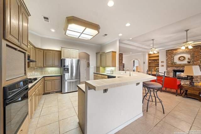 2001 Crown Rdg, Kerrville, TX 78028 - kitchen featuring stainless steel refrigerator with ice dispenser, black oven, arched walkways, a breakfast bar area, and a peninsula