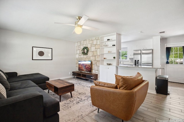 3003 Shady Spgs, San Antonio, TX 78230 - living area with a ceiling fan, light wood finished floors, a stone fireplace, and baseboards