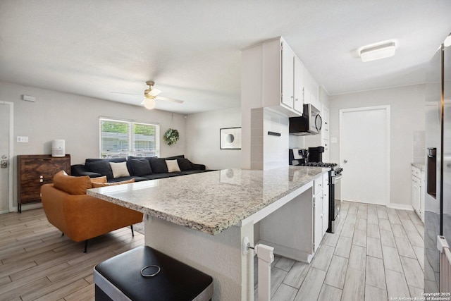 3003 Shady Spgs, San Antonio, TX 78230 - kitchen with appliances with stainless steel finishes, light wood finished floors, a ceiling fan, white cabinets, and light stone countertops