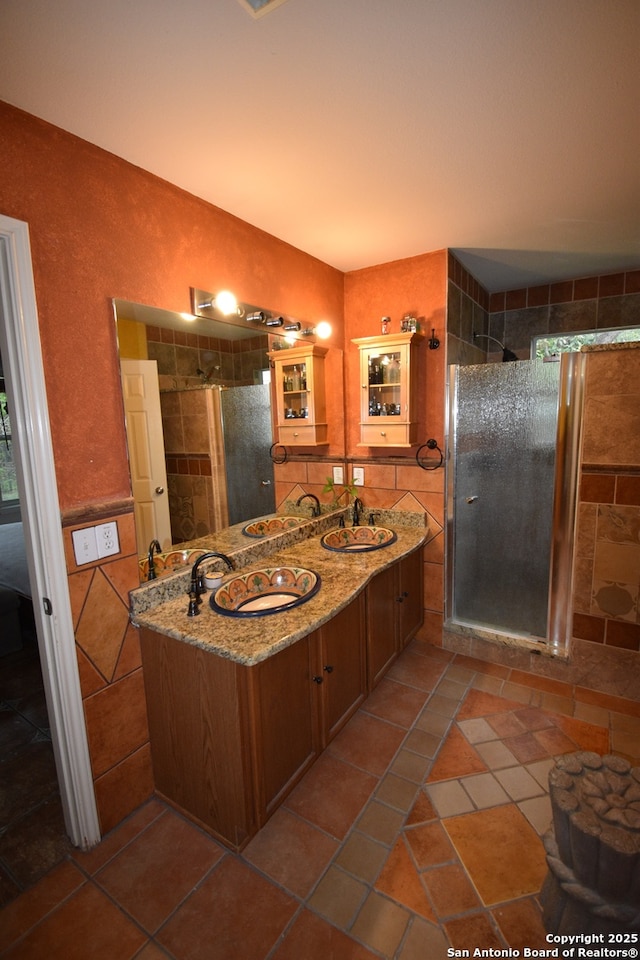 bathroom featuring tile walls, a stall shower, double vanity, and tile patterned floors