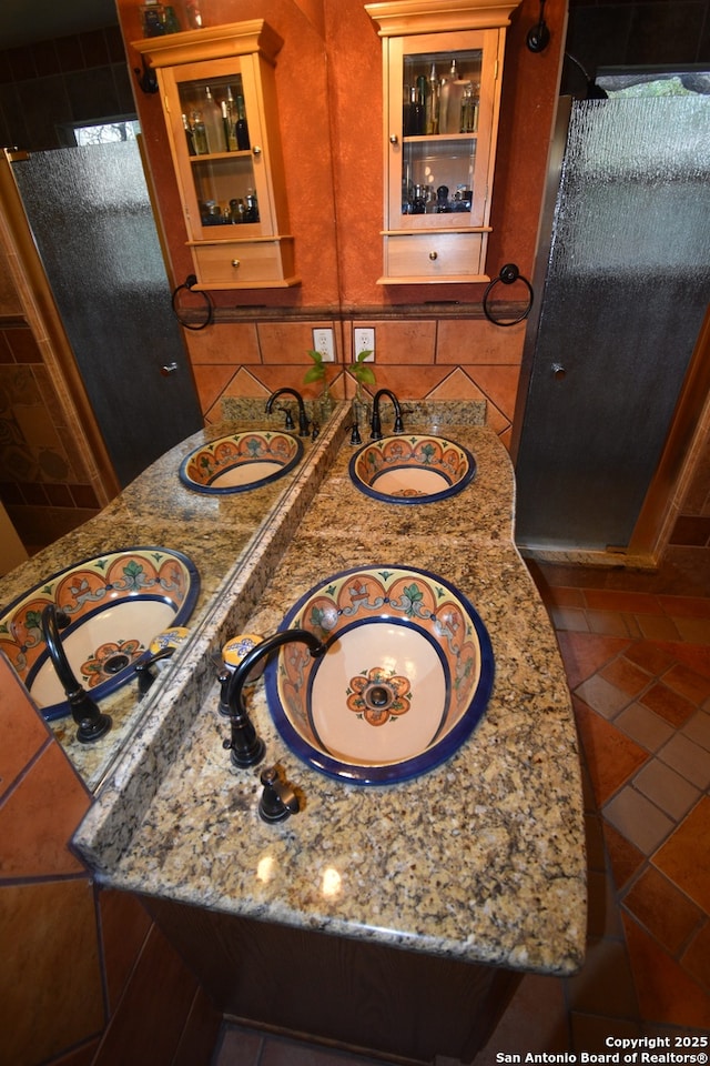 full bathroom with a shower stall, double vanity, and tasteful backsplash