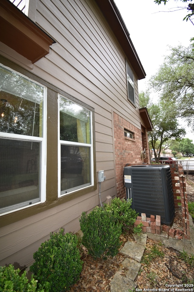 view of side of property with central AC unit and brick siding