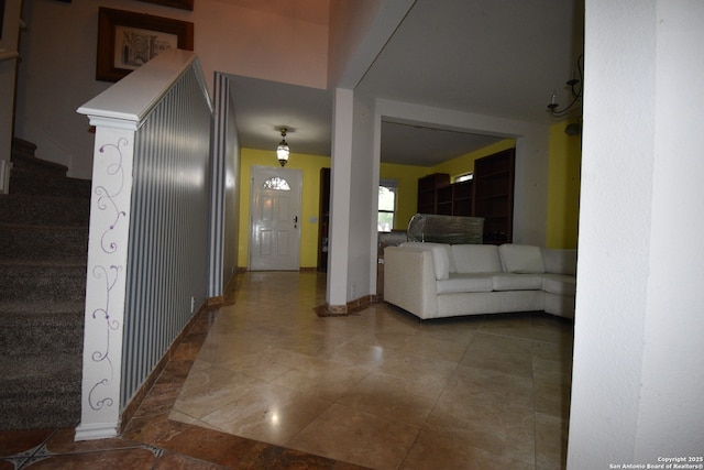 corridor featuring stairs, baseboards, and tile patterned flooring