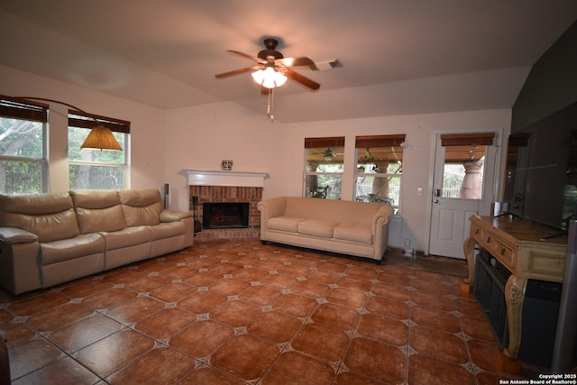 tiled living room featuring a ceiling fan, a brick fireplace, healthy amount of natural light, and vaulted ceiling
