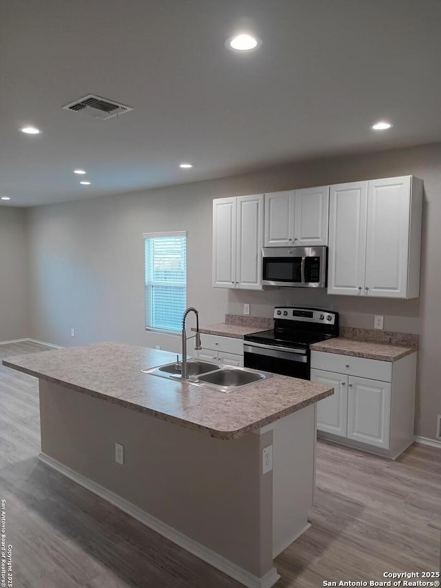 530 Pleasanton, San Antonio, TX 78221 - kitchen with appliances with stainless steel finishes, a sink, light wood-style flooring, white cabinetry, and light countertops