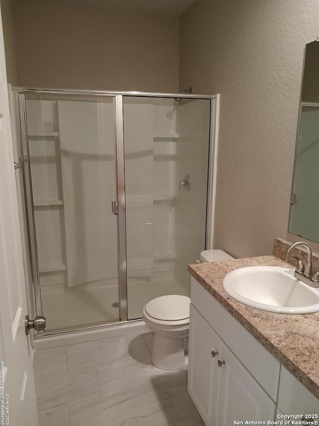 530 Pleasanton, San Antonio, TX 78221 - bathroom with a shower stall, a textured wall, vanity, toilet, and marble look tile flooring