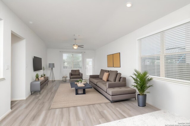 living room featuring light wood-type flooring, a ceiling fan, and baseboards