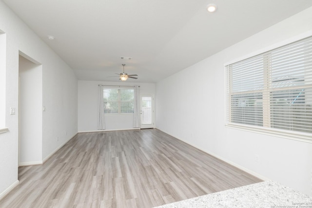 unfurnished room with light wood-style flooring, a ceiling fan, and baseboards