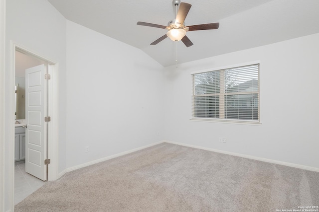 empty room featuring light colored carpet, vaulted ceiling, baseboards, and ceiling fan